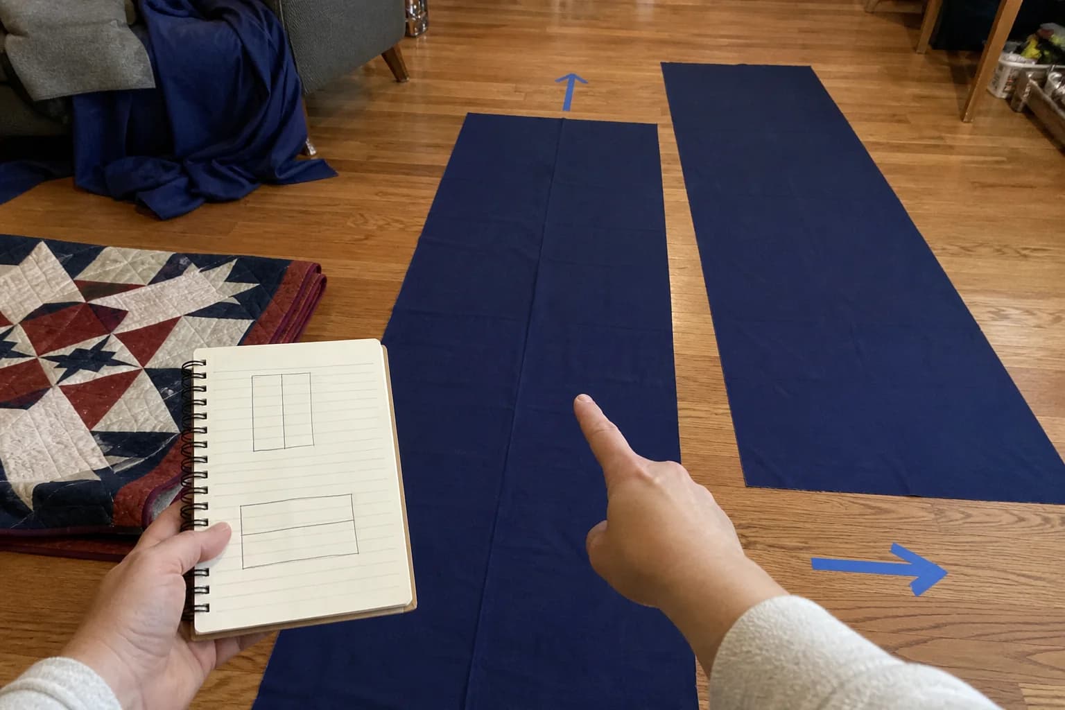 Backing fabric panels, a tape measure, and pencil notes arranged on a quilter's worktable.