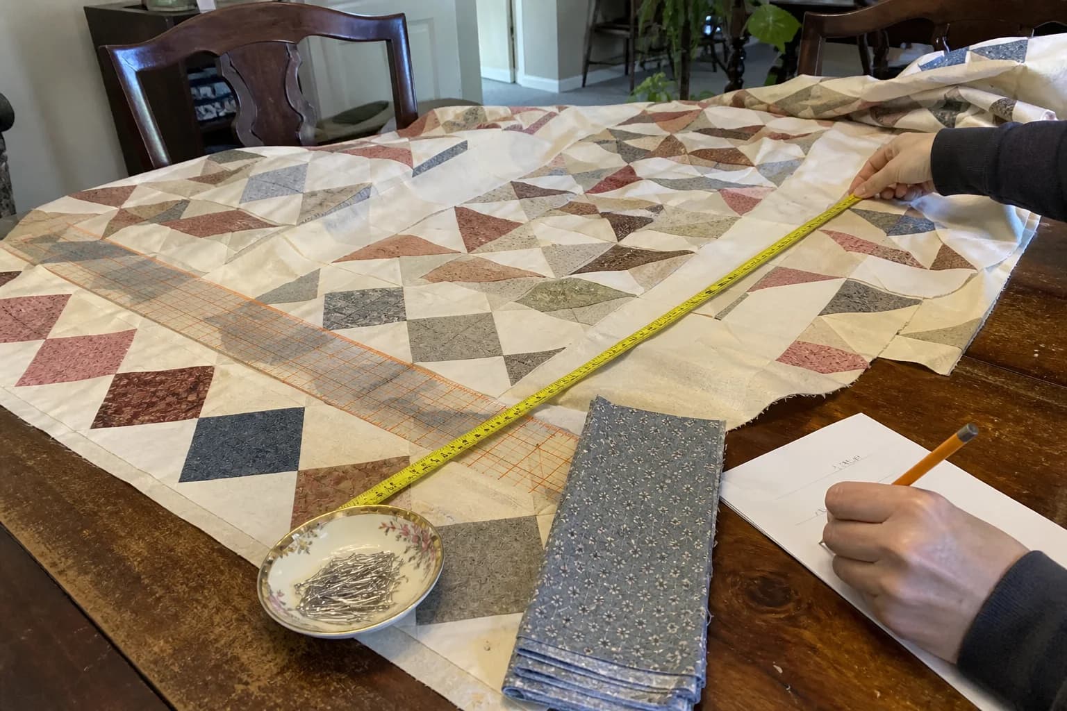 A quilter measures the center of a patchwork quilt top before planning border strips.